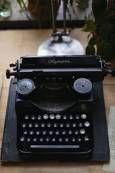 Classic black Olympia typewriter on wooden desk surrounded by plants, capturing a nostalgic vintage feel.