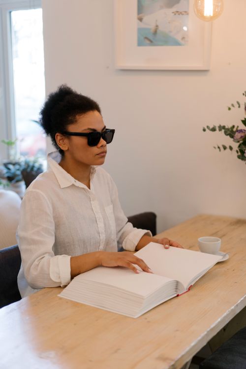 Free A visually impaired woman reads a Braille book in a cafe, embracing accessibility and literacy. Stock Photo