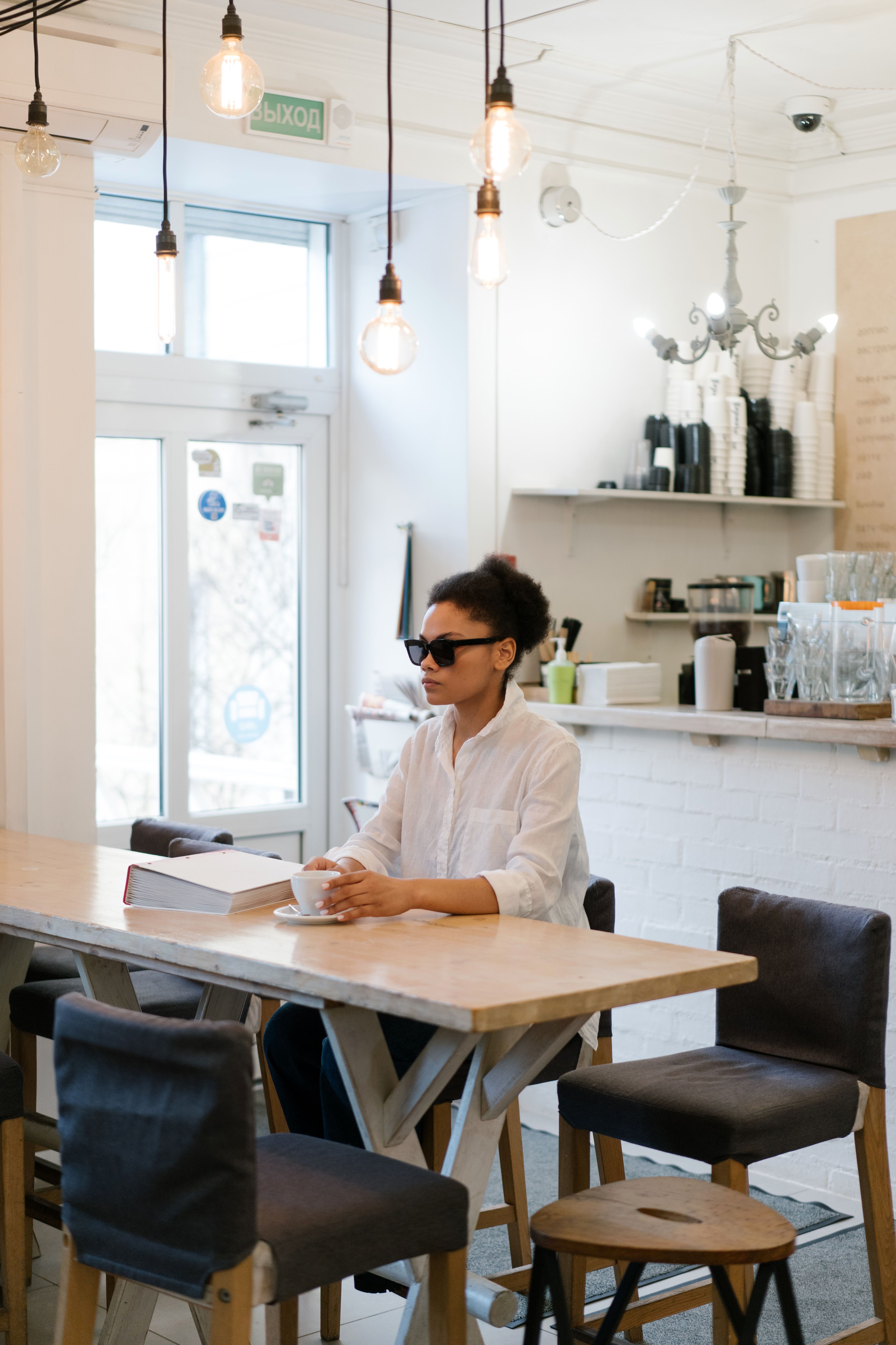 A Woman In White Long Sleeve Shirt Sitting on the Table · Free Stock Photo