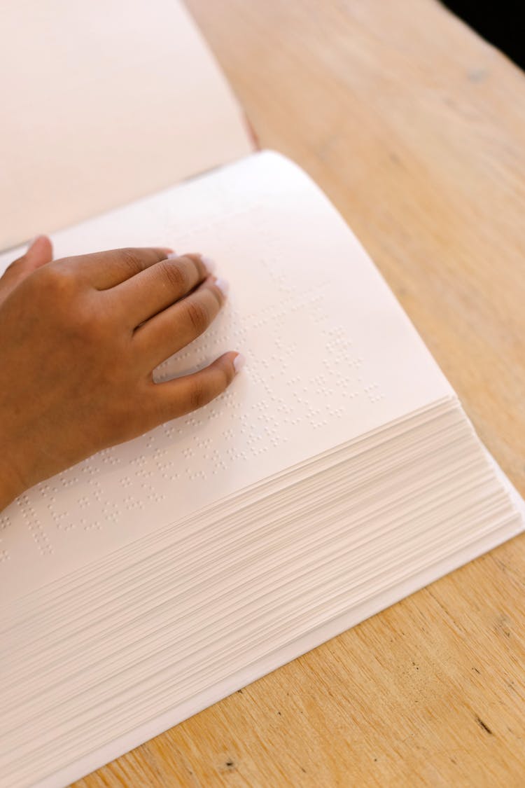 Close-Up Shot Of A Hand On A Braille Book