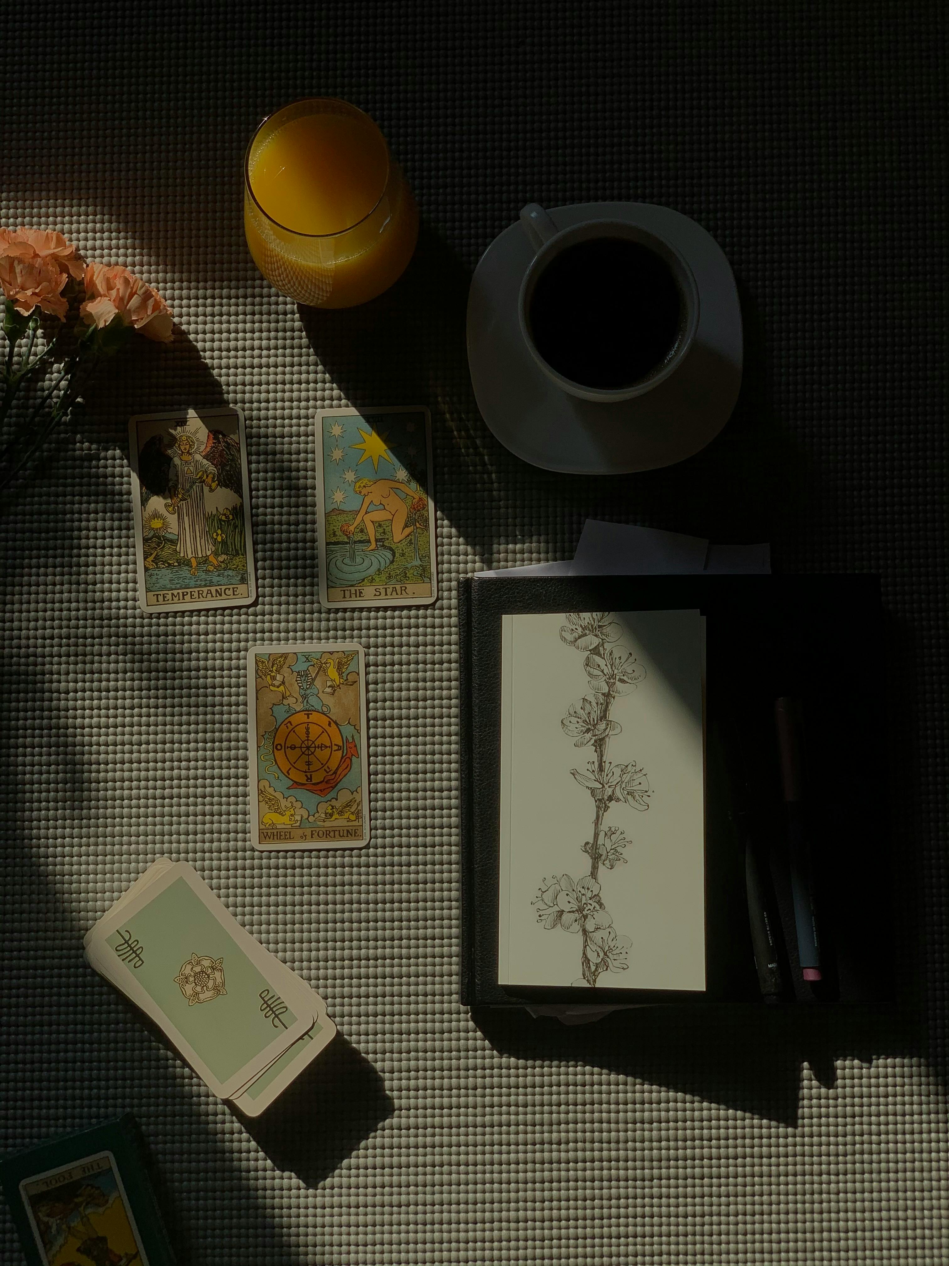 A mystical arrangement with tarot cards, coffee, and orange juice under warm lighting.