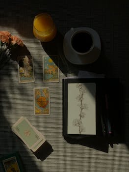 A mystical arrangement with tarot cards, coffee, and orange juice under warm lighting.