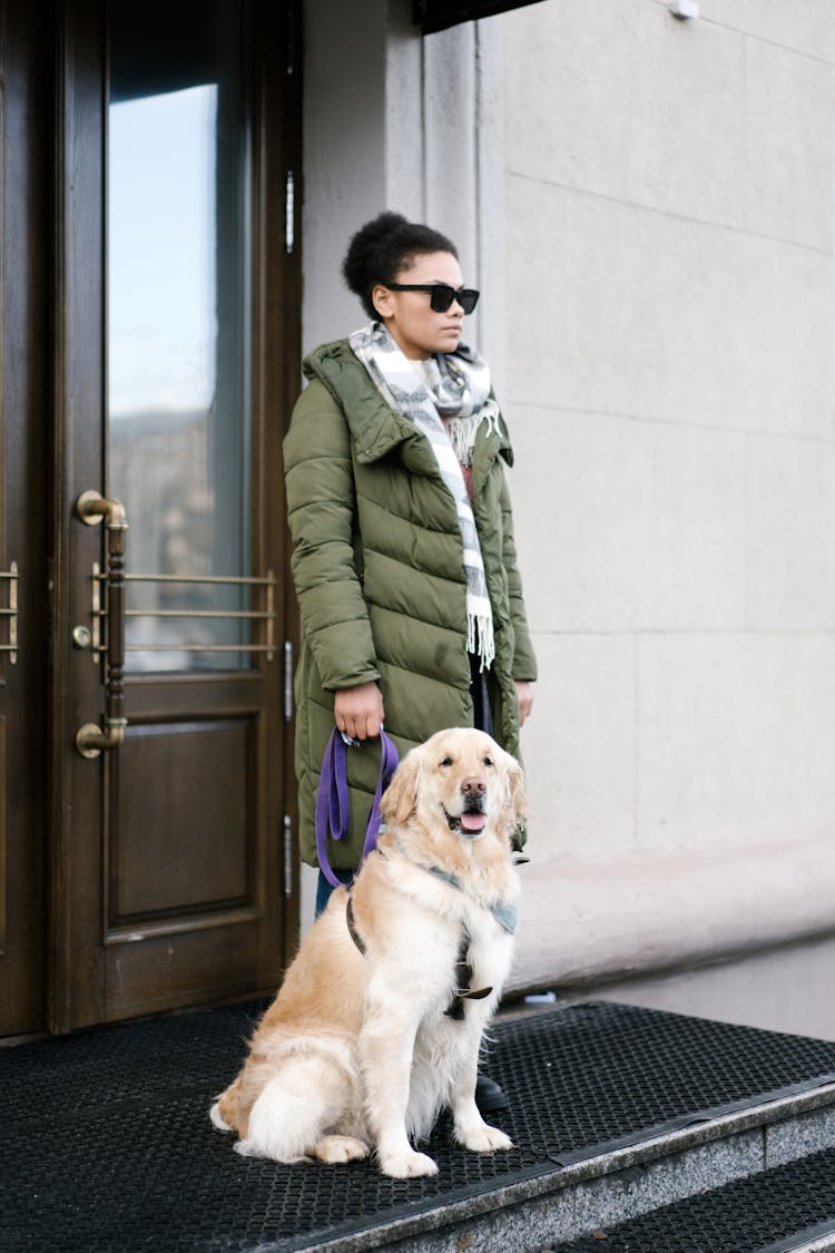 Man In Green Coat Holding Brown Dog Near Door 