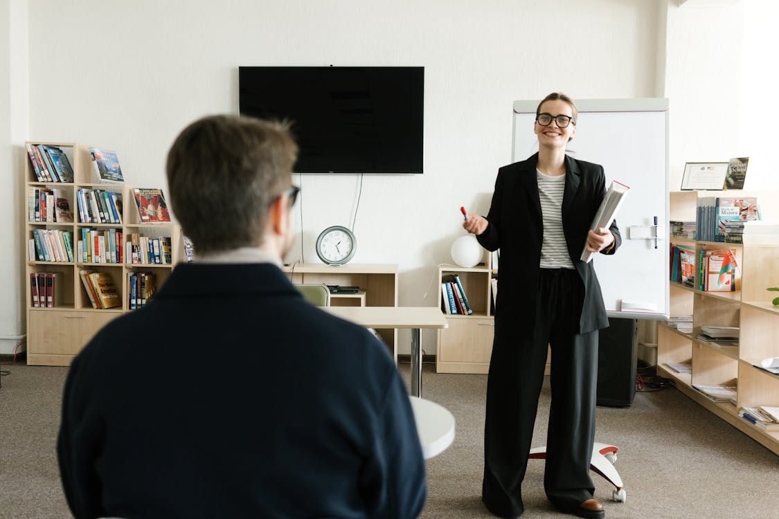 Free Businesswoman giving presentation in office with bookshelves and clock. Stock Photo Free Businesswoman giving presentation in office with bookshelves and clock. Stock Photo