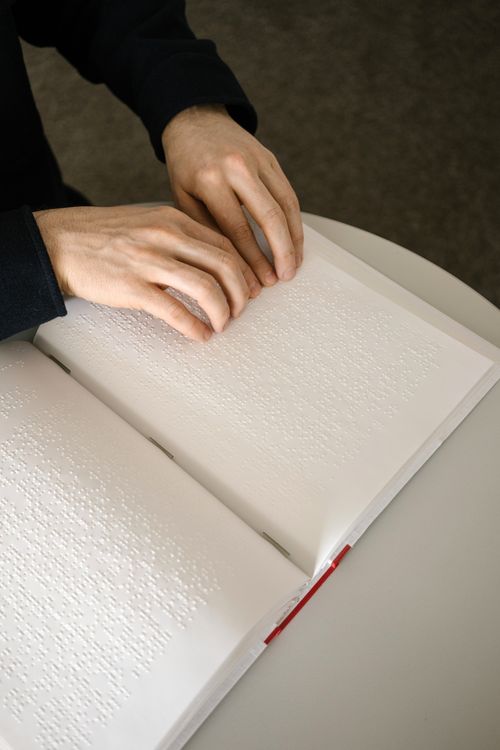 Free Close-up of hands reading a braille book, symbolizing accessibility and inclusivity. Stock Photo