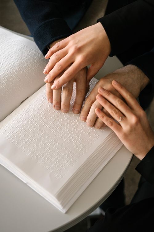 Free Close-up of hands reading a Braille book, symbolizing accessibility and learning. Stock Photo