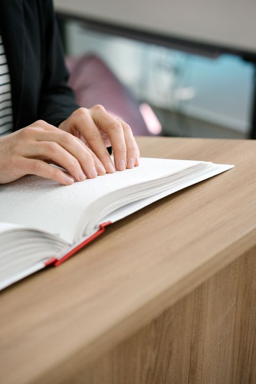 Free Hands touching Braille text on an open book, focusing on the sense of touch and accessibility. Stock Photo