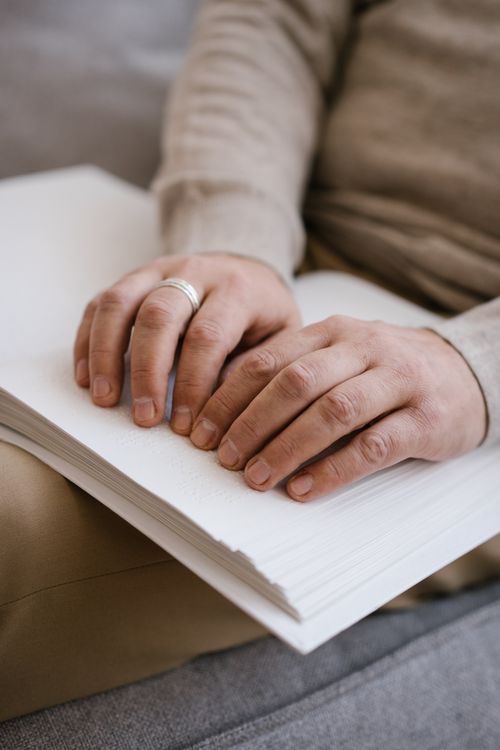 Free Focused shot of hands reading a Braille book, representing inclusion and accessibility. Stock Photo
