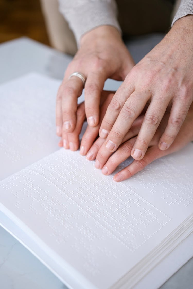 Close-up Photo Of Hands On A Braille 