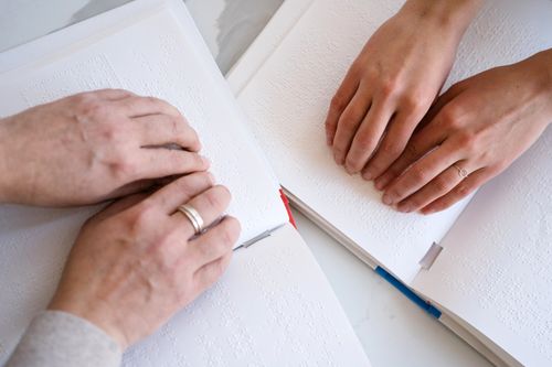 Free Hands reading braille books emphasize the tactile experience of blindness and disability. Stock Photo