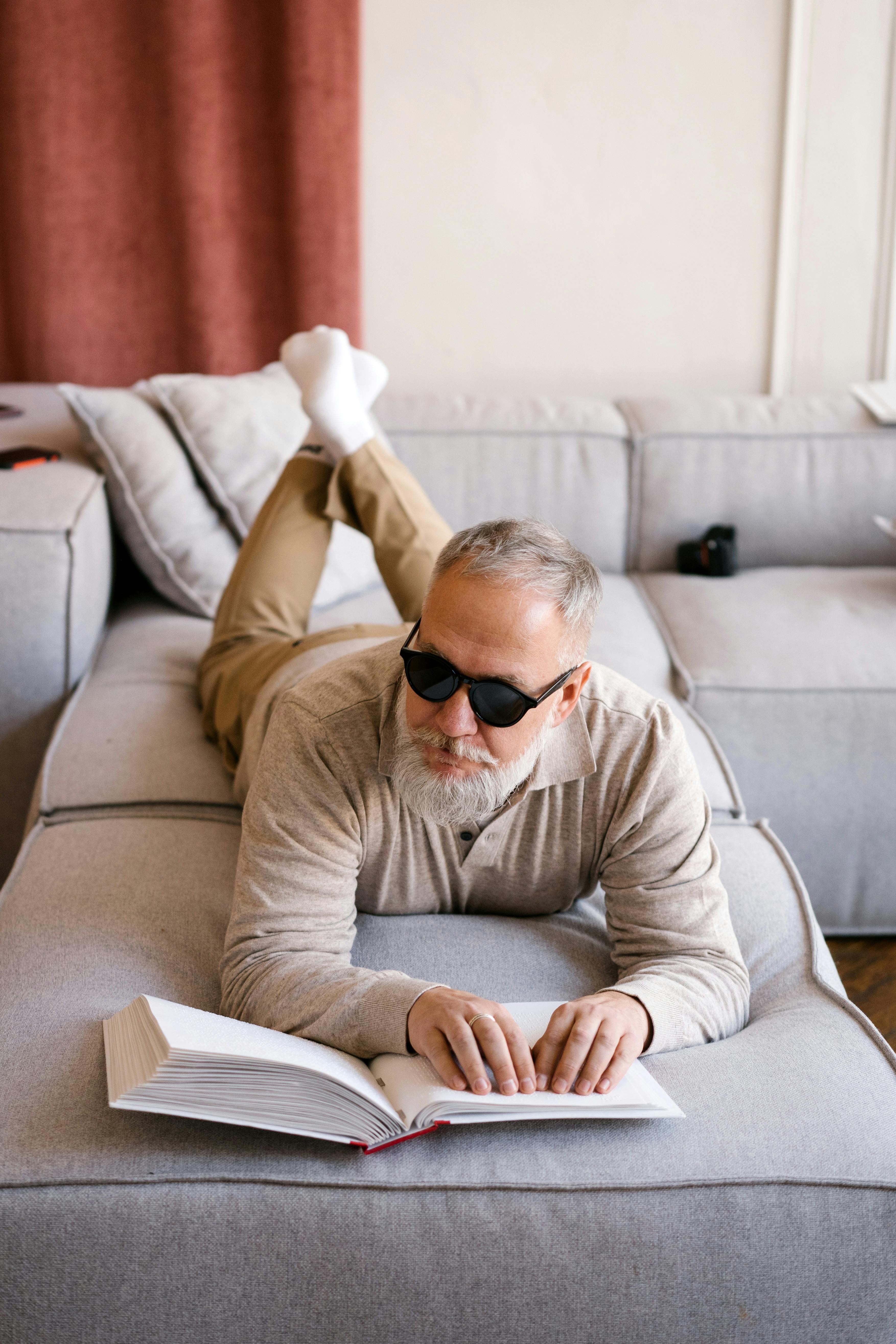 man in brown sweater wearing black sunglasses sitting on couch