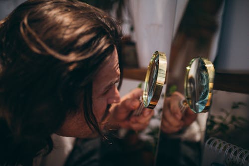 Free A Long Haired Man Holding a Magnifying Glass  Stock Photo