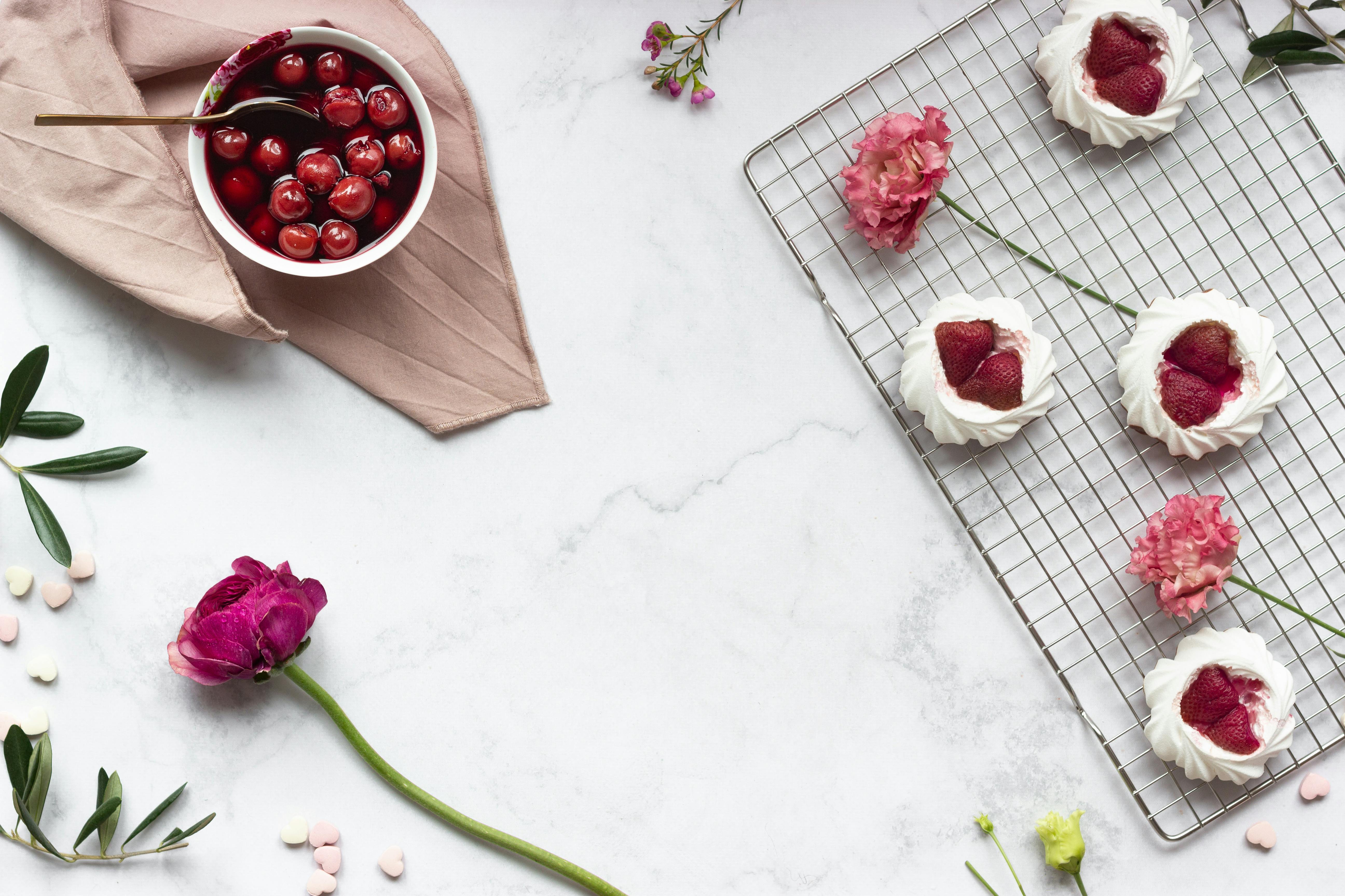 Artistic flat lay of meringues with strawberries and cherries on a marble surface. Perfect for dessert lovers.