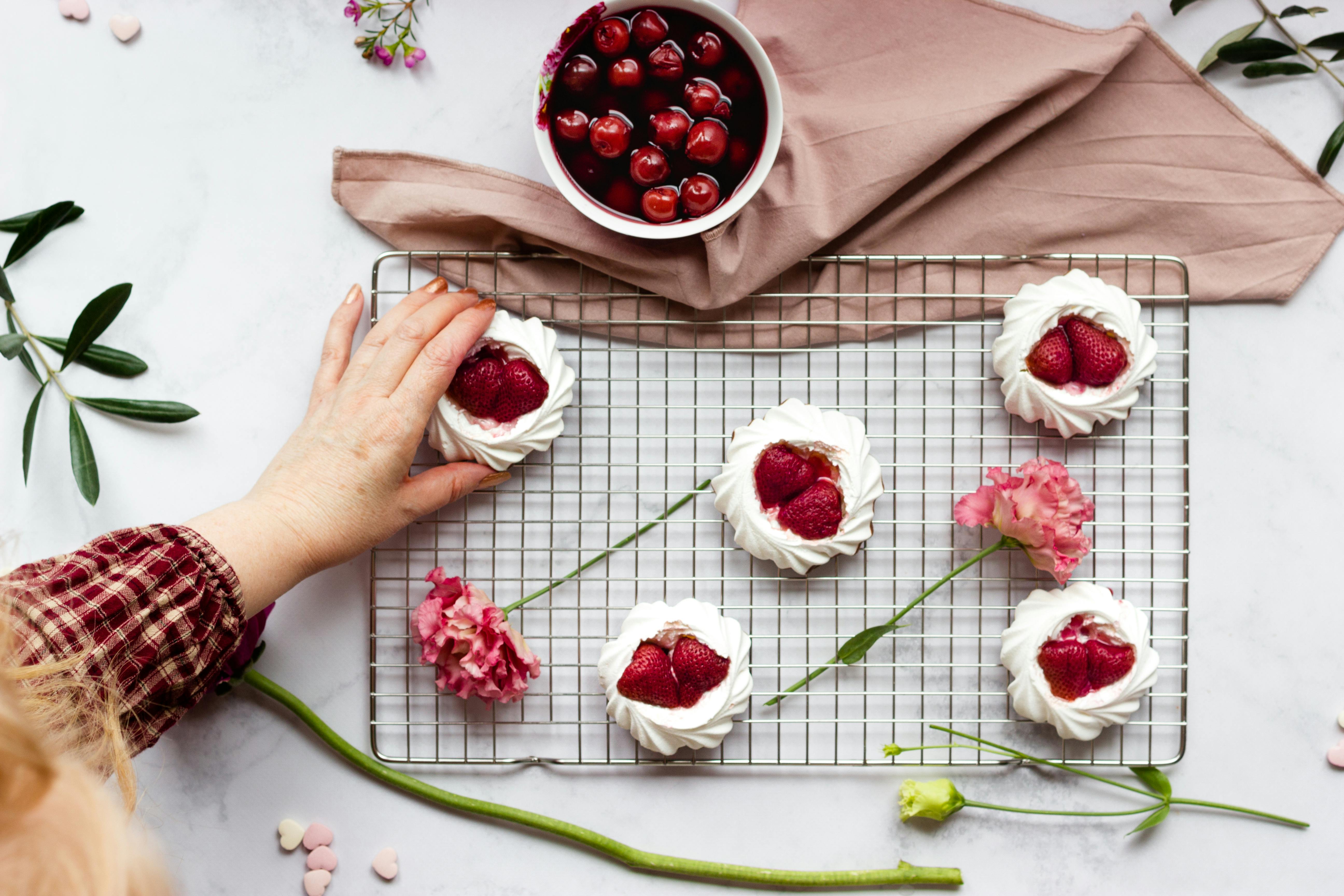 Flat lay of strawberry pavlova desserts with floral decoration, ideal for food photography.