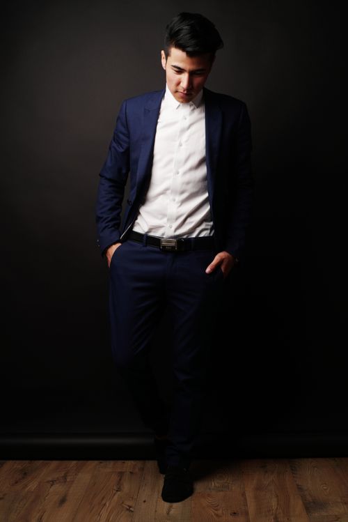 Free A fashionable man in a suit poses against a dark studio backdrop, exuding sophistication. Stock Photo