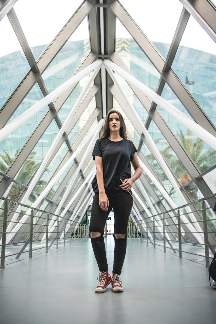 Woman In Ripped Jeans And T Shirt Standing Near The Metal Railing