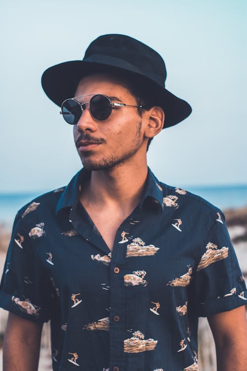Man in Blue Button Up Shirt Wearing Black Sunglasses and Black Hat