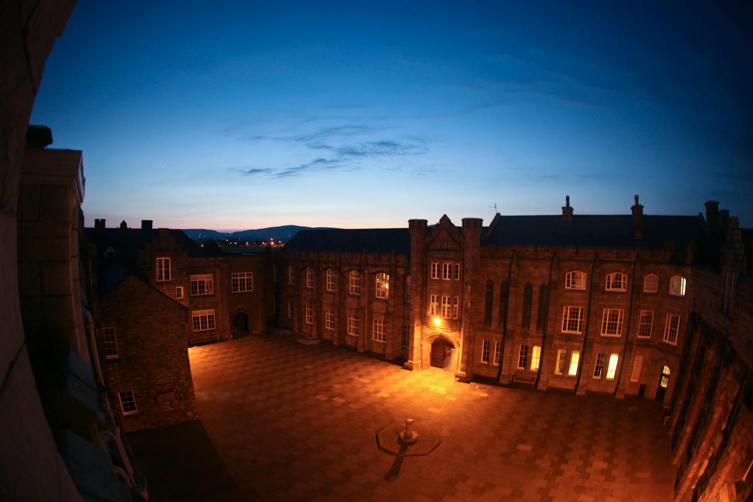 Historic college courtyard at twilight with architectural beauty and warm lighting