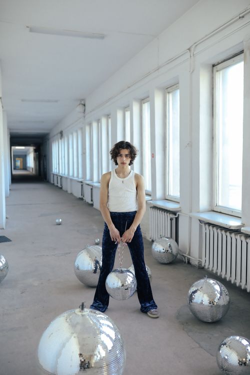 Free Caucasian man in a hallway surrounded by disco balls, wearing jeans and a tank top. Stock Photo