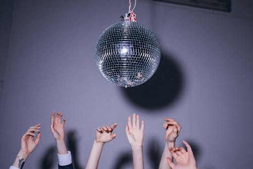 People With Their hands near the Disco Ball