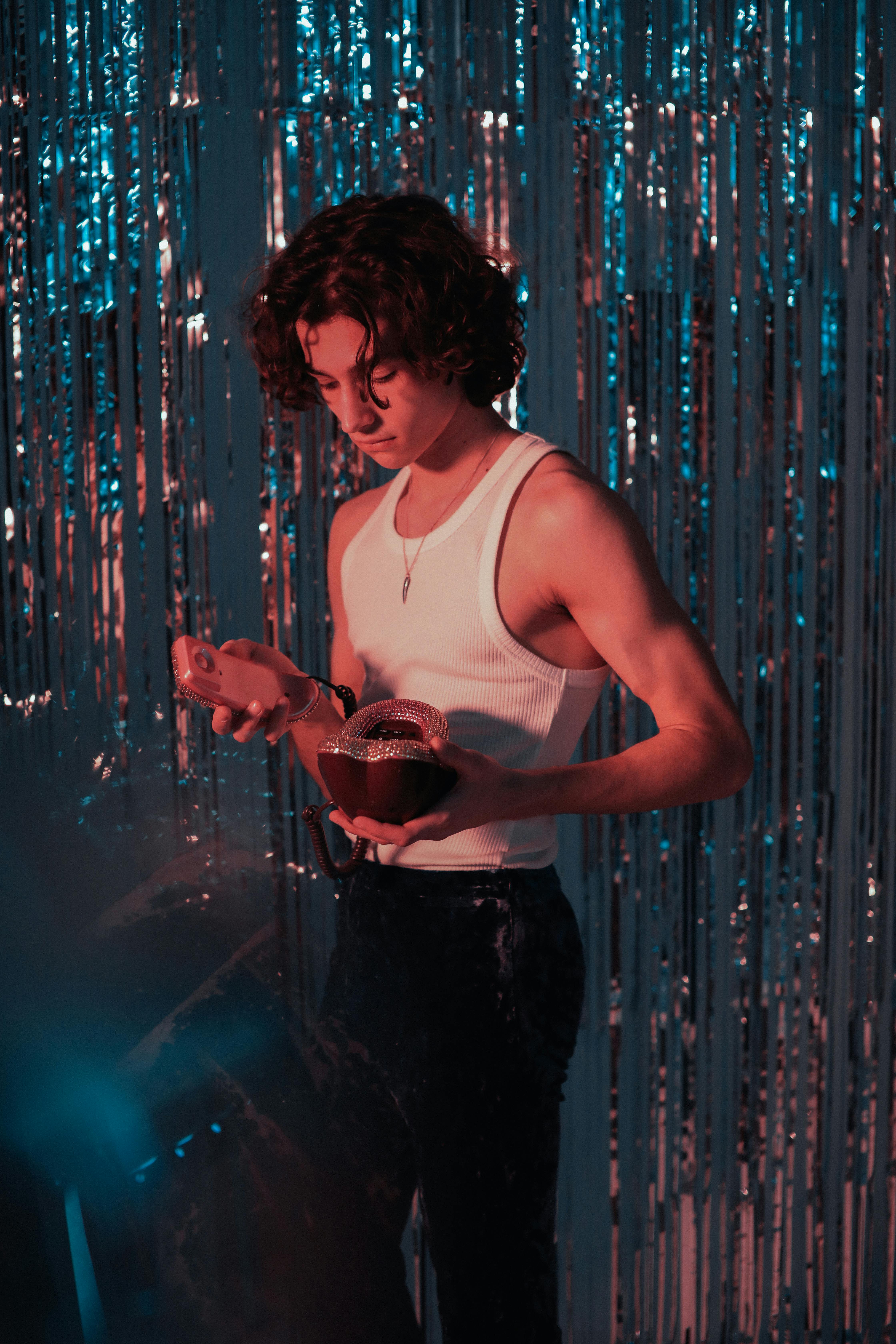 man in white tank top and black shorts standing in front of blue and green lights