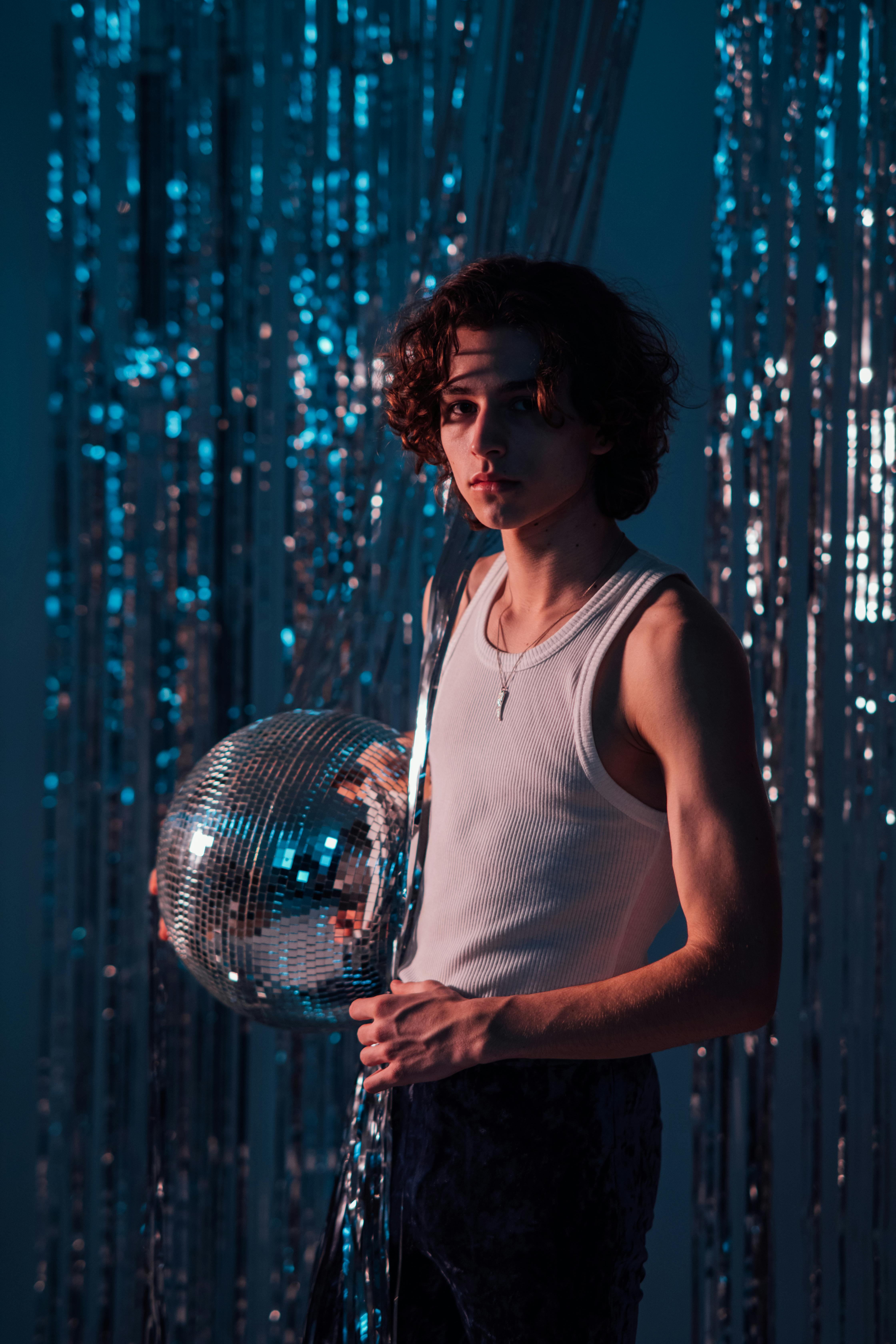 man in white tank top holding a disco ball