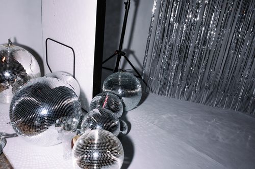 Free Cluster of disco balls and silver foil curtain in a studio setting creating a reflective atmosphere. Stock Photo