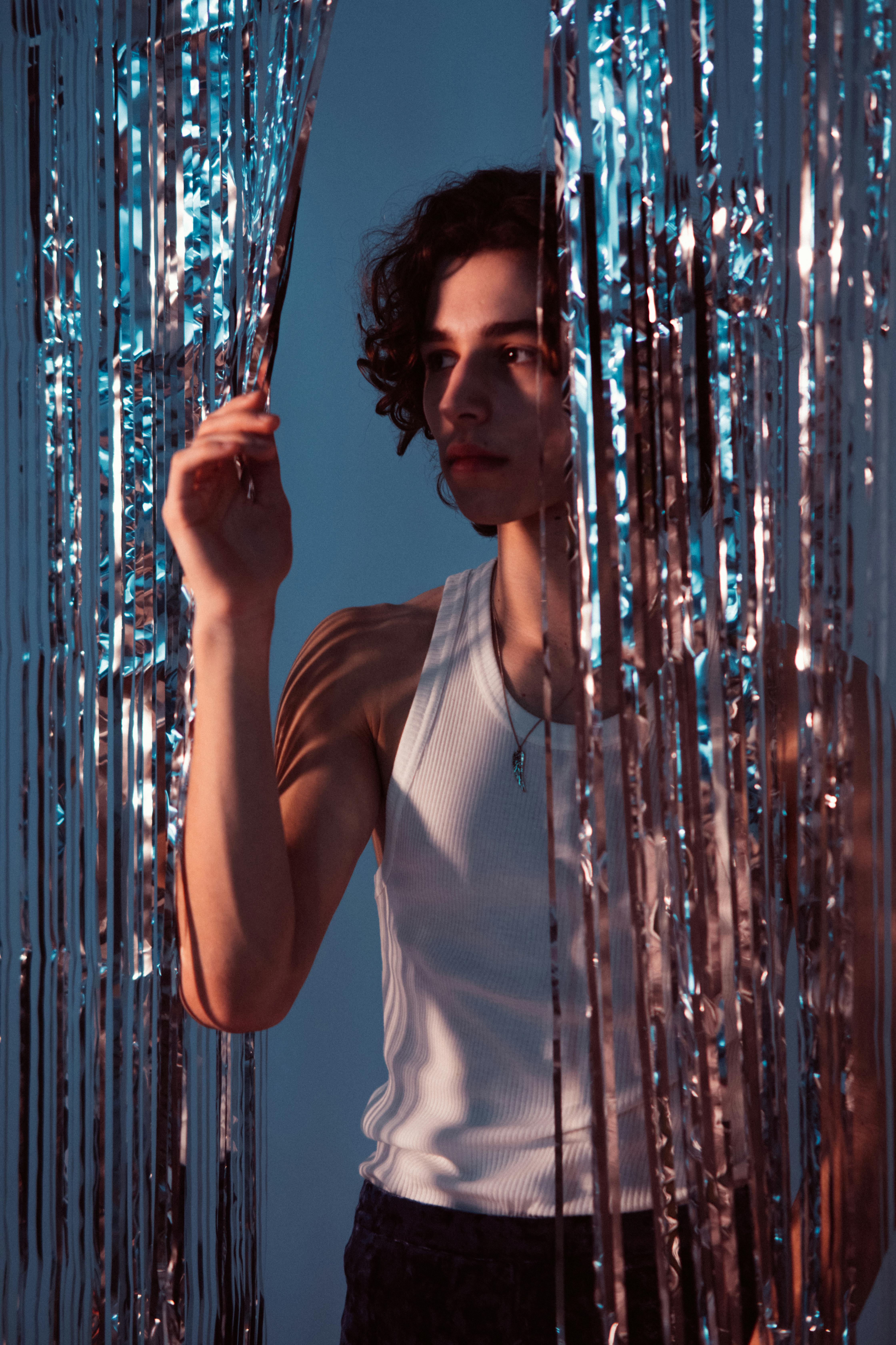 woman in white tank top standing near blue string lights