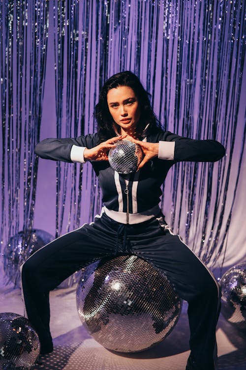 Woman in a Tracksuit Holding a Disco Ball