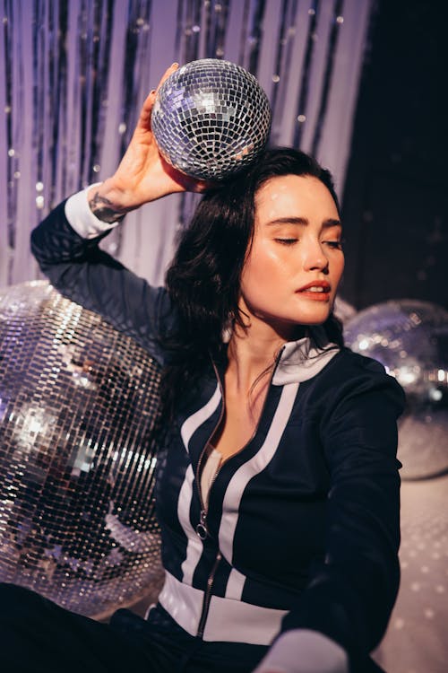 Woman in Tracksuit Holding a Disco Ball