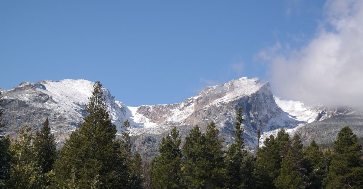 Majestic snow-capped mountains and evergreen trees in Estes Park, Colorado.