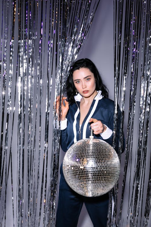 Photo of a Woman Carrying a Disco Ball