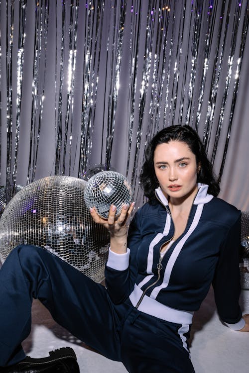 Photograph of a Woman in a Tracksuit Holding a Disco Ball