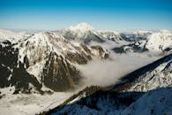 在晴朗的蓝天下，奥地利蒂罗尔州的山脉和山谷覆盖着皑皑白雪，呈现出令人惊叹的冬季景色