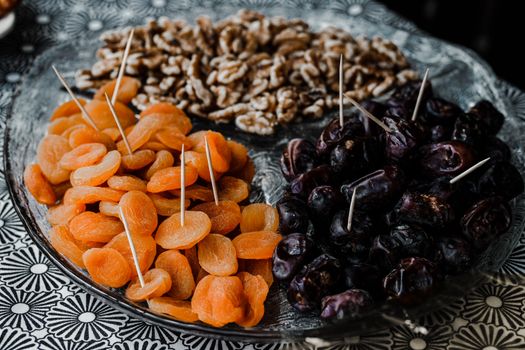 A close-up of dried apricots, prunes, and walnuts on a decorative plate.