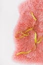 Top view composition of yellow tailors meter placed on pink fluffy carpet on white surface