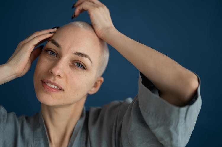 Smiling Bald Woman Touching Head In Studio