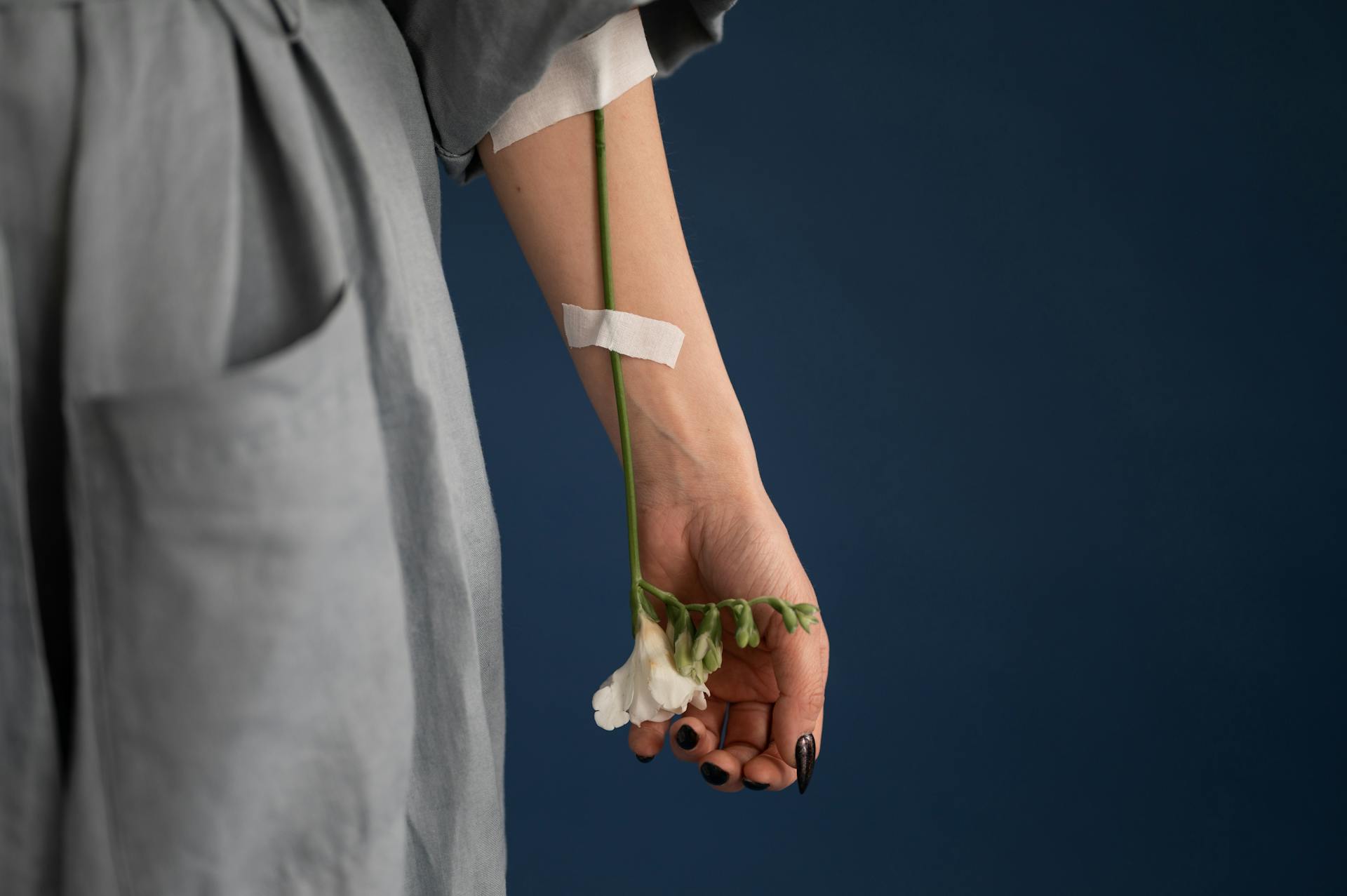 Crop unrecognizable woman with flower attached to arm with plaster