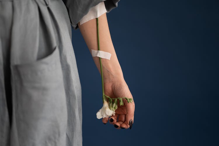 Crop Unrecognizable Woman With Flower Attached To Arm With Plaster