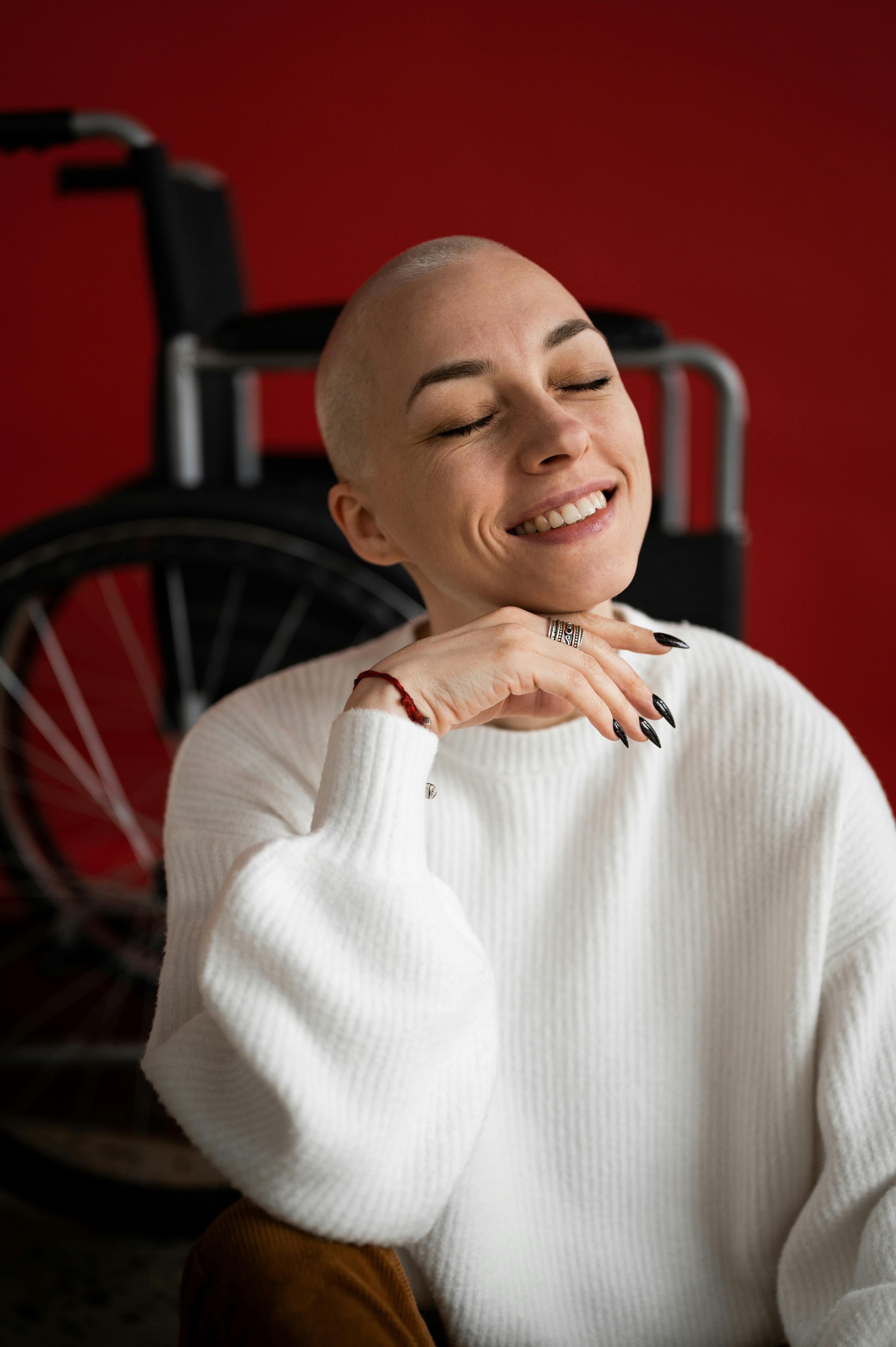 cheerful woman smiling while sitting near wheelchair after recovery