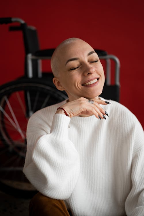 Cheerful woman smiling while sitting near wheelchair after recovery
