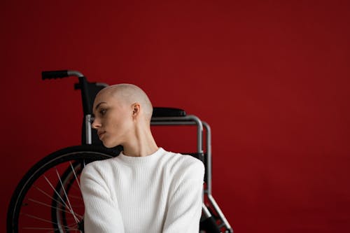 Melancholic woman leaning on wheelchair and looking away pensively