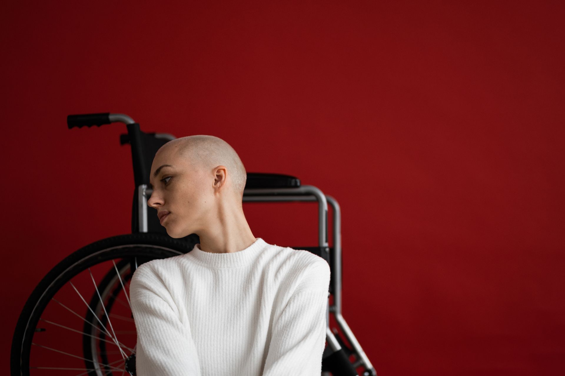 Melancholic woman leaning on wheelchair and looking away pensively