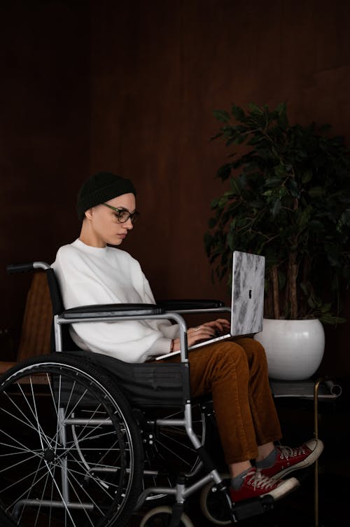 Serious woman with disability working online on laptop