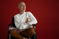 Female in wheelchair grimacing with tongue out and middle finger