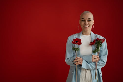 Smiling female standing with fresh poppies against red background