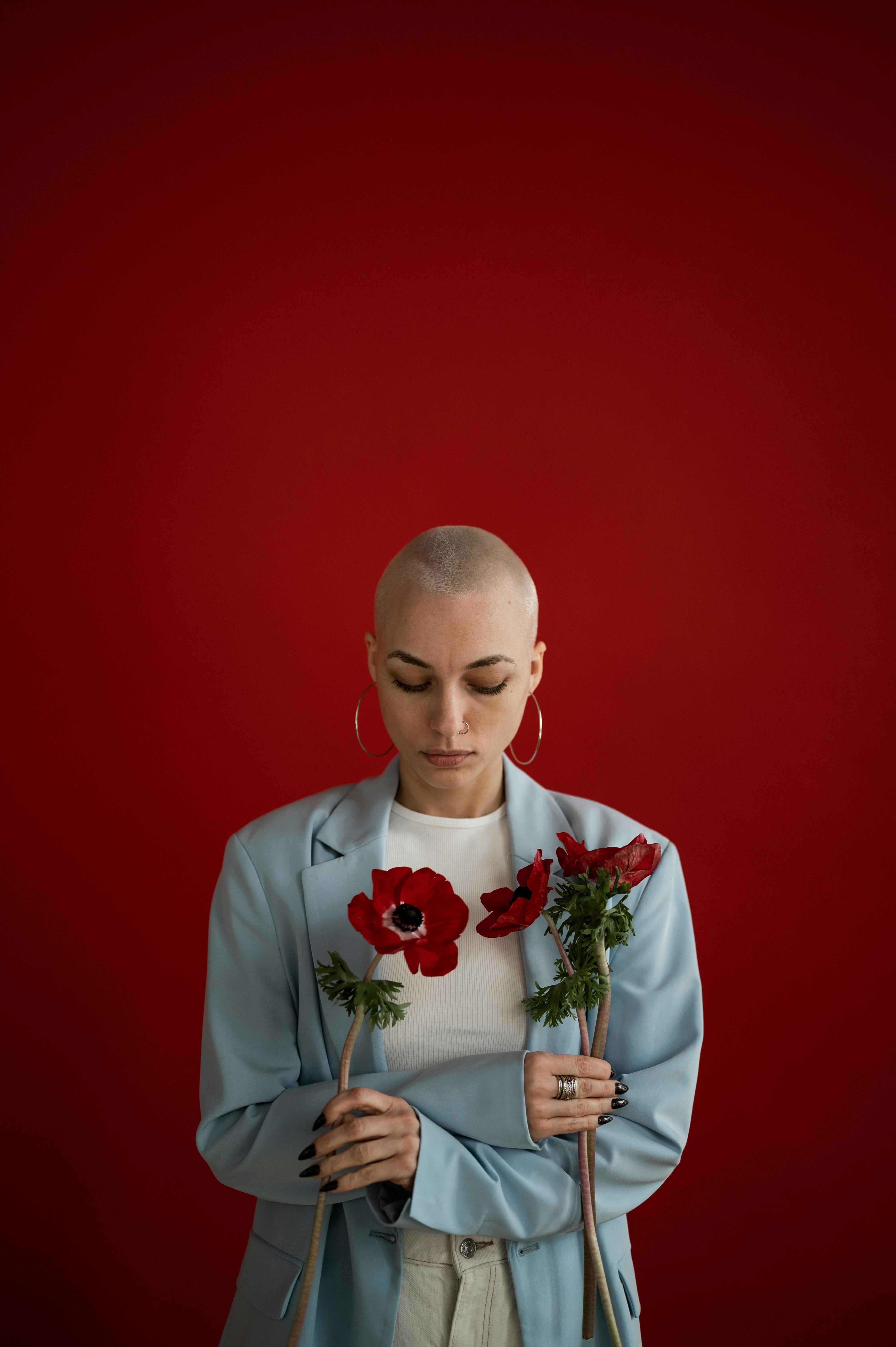 [ColoSach]-pensive-woman-with-short-hair-in-stylish-clothes-standing-with-bright-red-poppies-in-studio-against-red-background