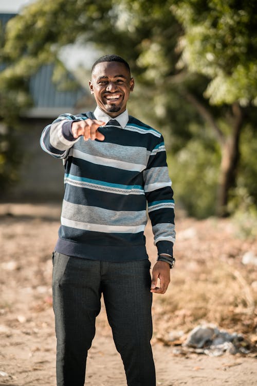 Man in Checkered Long Sleeves Smiling while Pointing Finger at the Camera