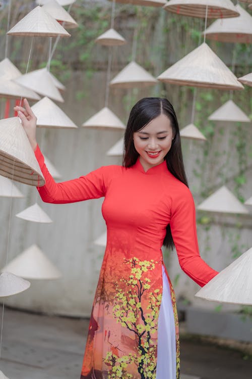 Woman in Red Dress Standing Beside Hanging Hats