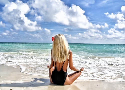 Free Woman Wearing Black Monokini Meditating on in Front of Sea Under Blue and White Sky Stock Photo